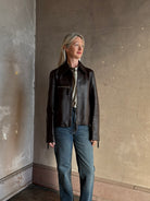 Mature woman wearing Proenza Schouler White Label Annabel lambskin Leather biker Jacket in Chocolate Brown with two way front zipper and straight hem