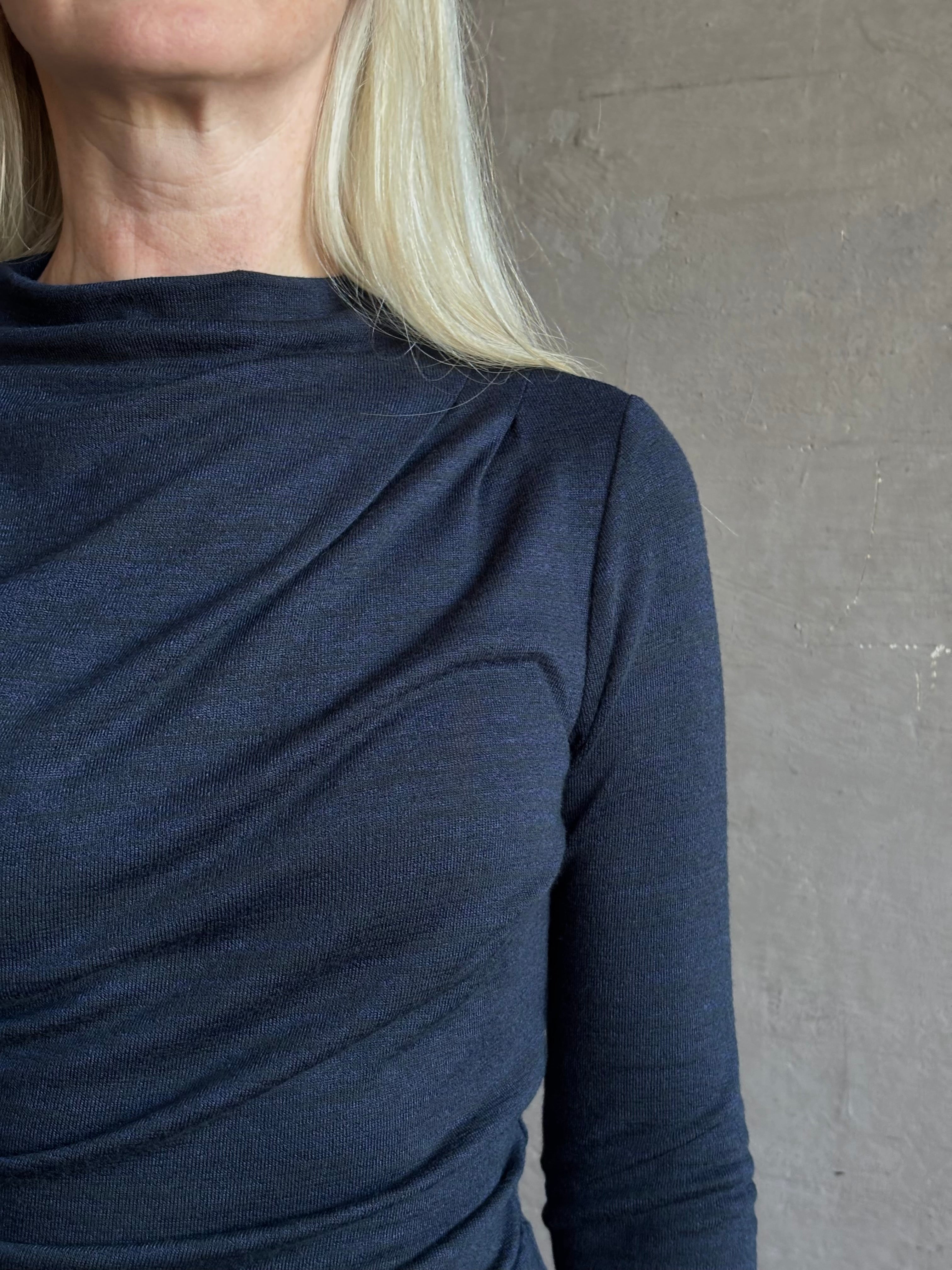 Close-up of a mature woman wearing Proenza Schoulder WL Mimi jersey top dark navy blue top showing the draped neckline and shoulder detail