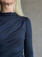 Close-up of a mature woman wearing Proenza Schoulder WL Mimi jersey top dark navy blue top showing the draped neckline and shoulder detail