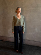 Mature woman wearing Rachel Comey Uridge Cardigan in Stone Green RWS-certified merino blend with U-neckline everyday layering