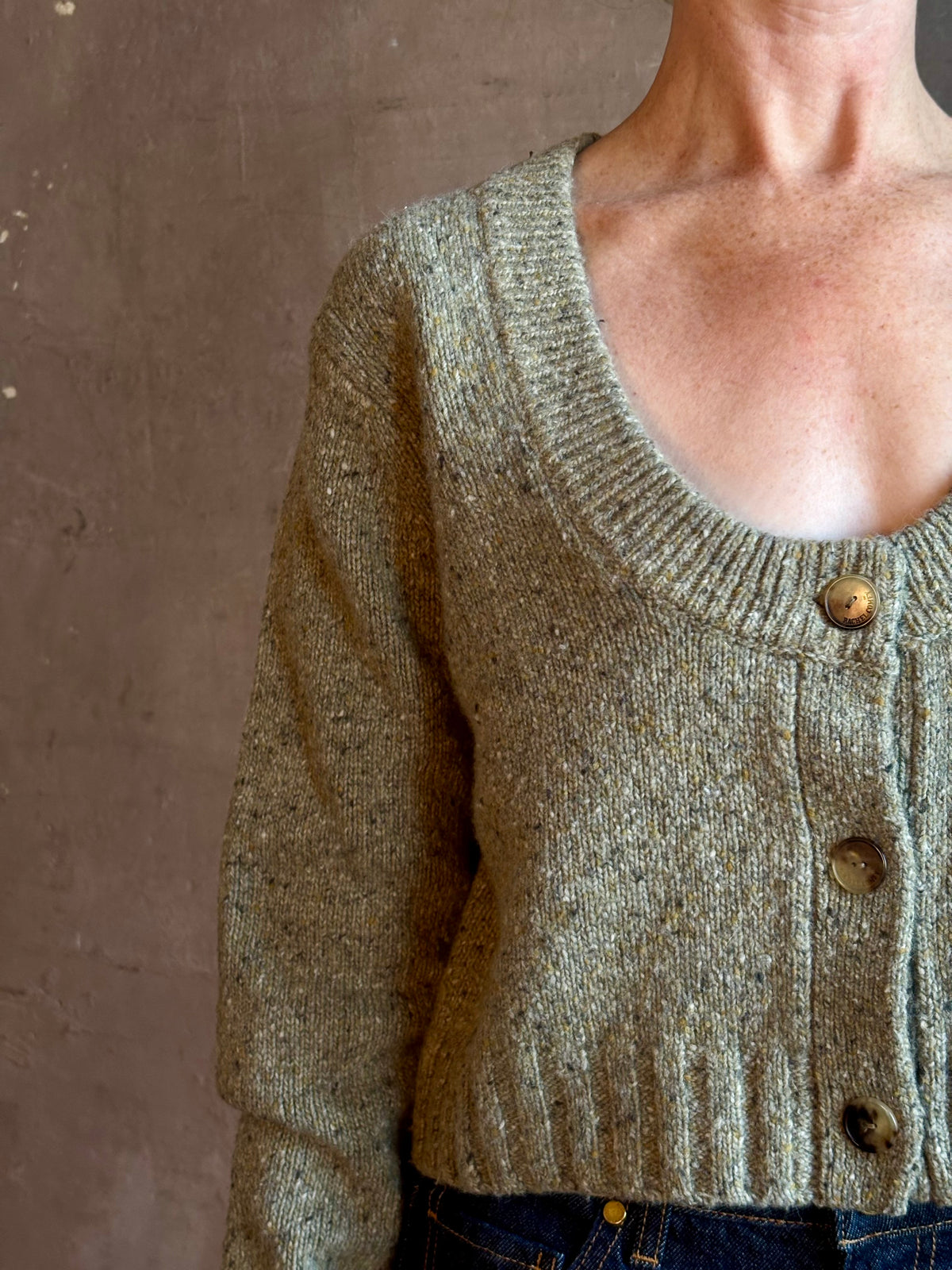 Mature woman wearing Rachel Comey Uridge Cardigan in Stone Green RWS-certified merino blend with U-neckline everyday layering