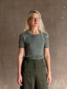 Mature woman  wearing a textured short-sleeve fitted knit top in sage green round neckline with brown heathering