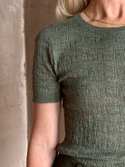 Mature woman  wearing a textured short-sleeve fitted knit top in sage green round neckline with brown heathering