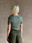 Mature woman  wearing a textured short-sleeve fitted knit top in sage green round neckline with brown heathering