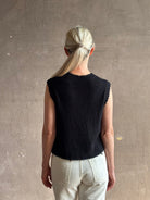 Mature woman wearing Rachel Comey designer Relent sleeveless black cotton knit top with a scalloped edges 