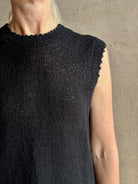 Mature woman wearing Rachel Comey designer Relent sleeveless black cotton knit top with a scalloped edges 