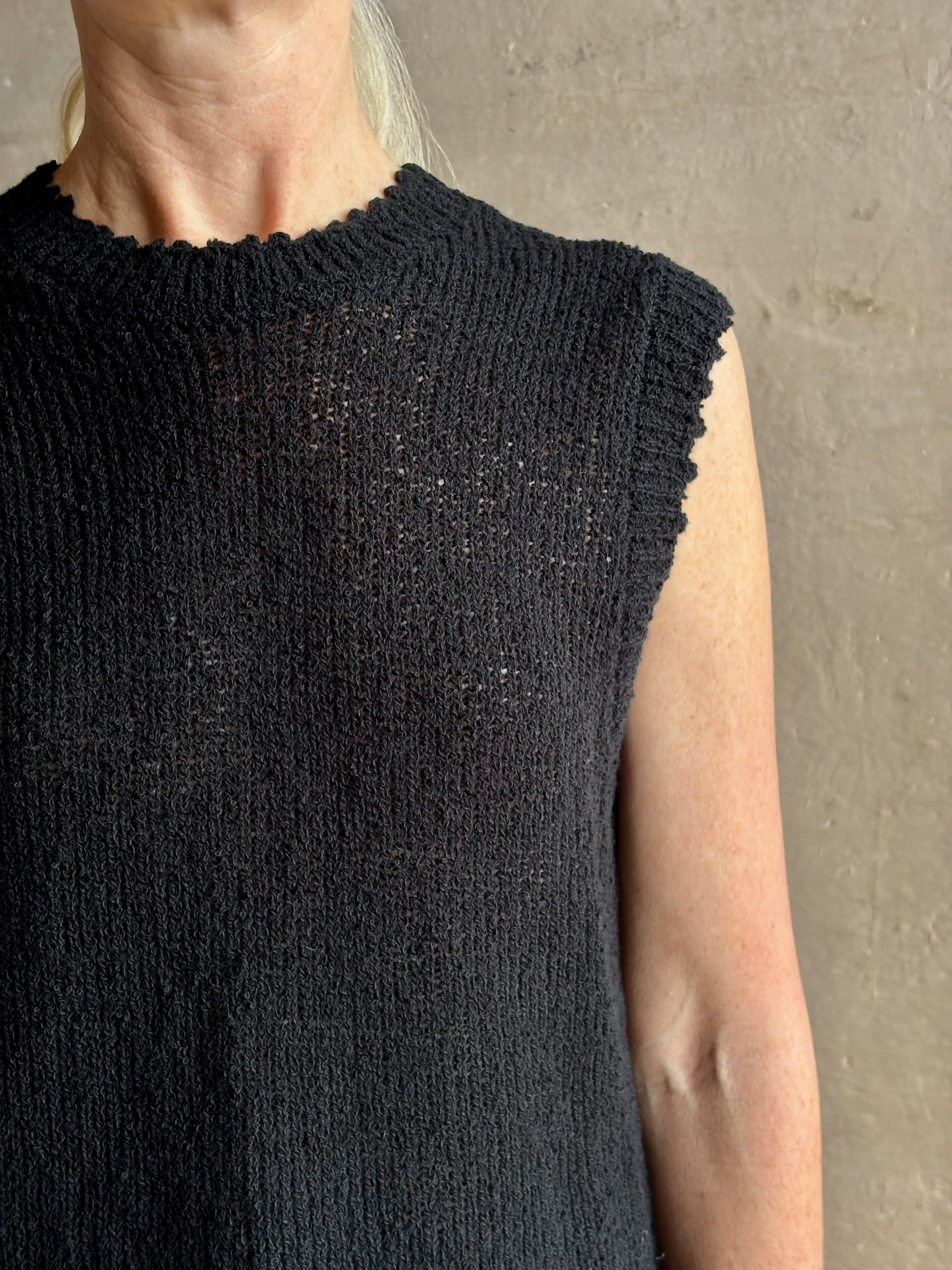 Mature woman wearing Rachel Comey designer Relent sleeveless black cotton knit top with a scalloped edges 