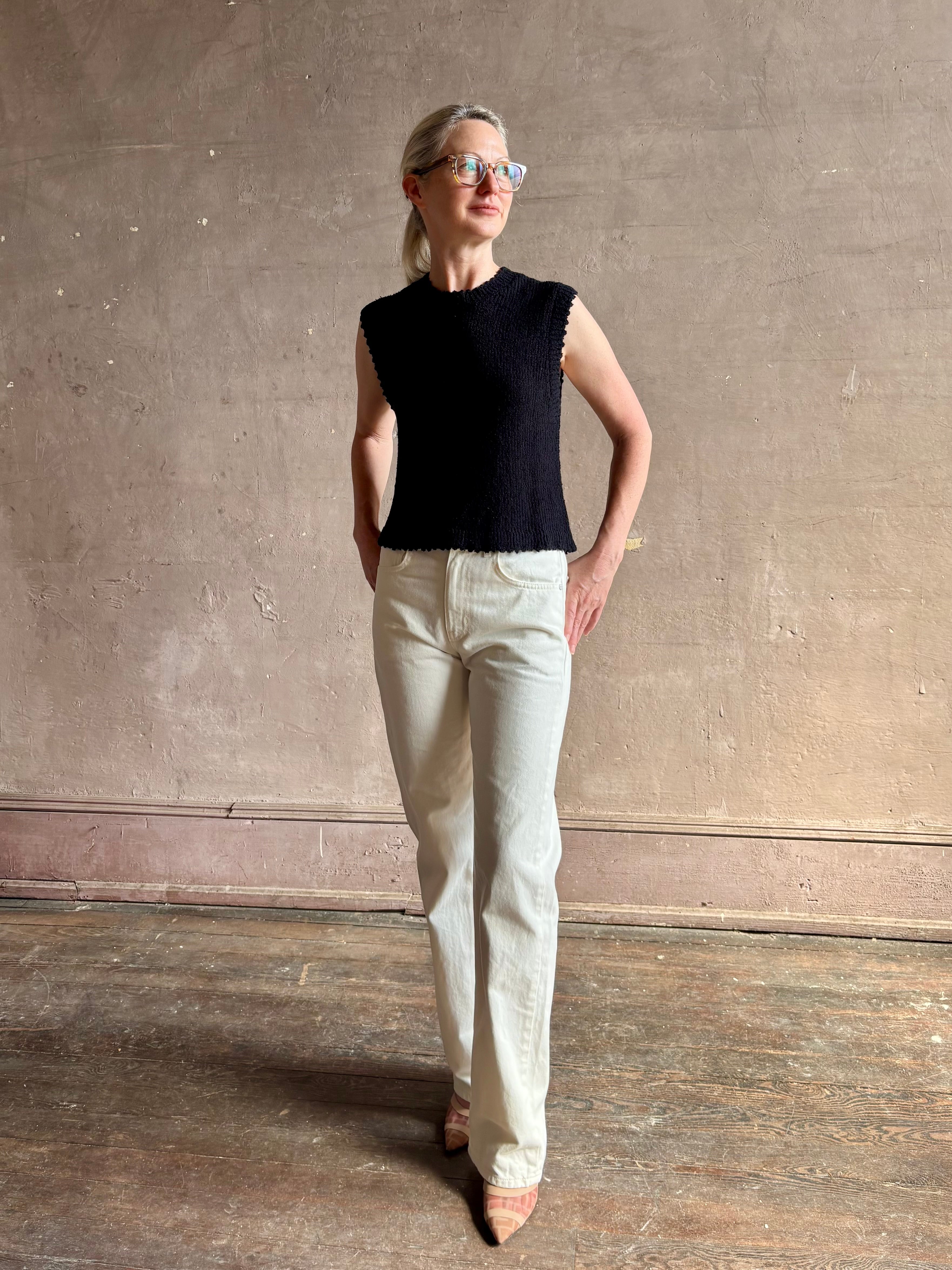 Mature woman wearing Rachel Comey designer Relent sleeveless black cotton knit top with a scalloped edges 