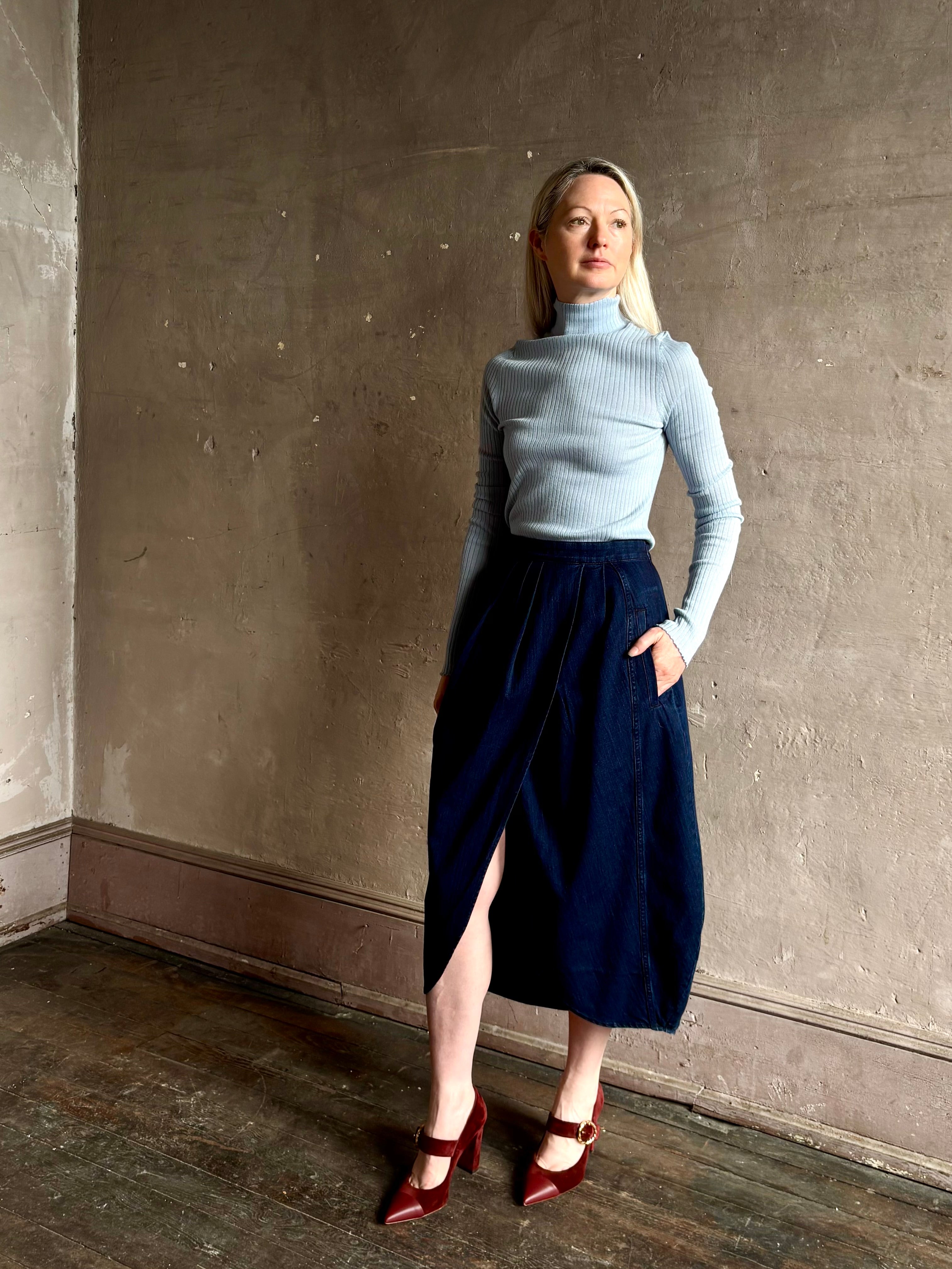 Woman wearing Rachel Comey dark wash denim midi Sobre skirt wrap-style front slit tulip design and side pockets