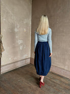 Woman wearing Rachel Comey dark wash denim midi Sobre skirt wrap-style front slit tulip design and side pockets
