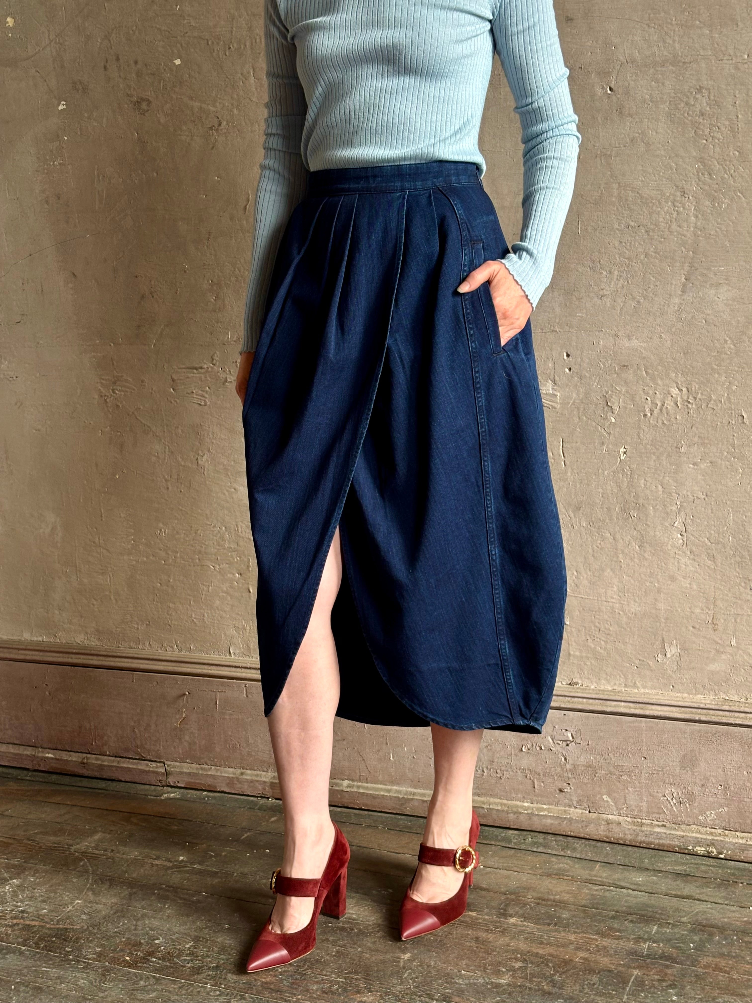 Woman wearing Rachel Comey dark wash denim midi Sobre skirt wrap-style front slit tulip design and side pockets