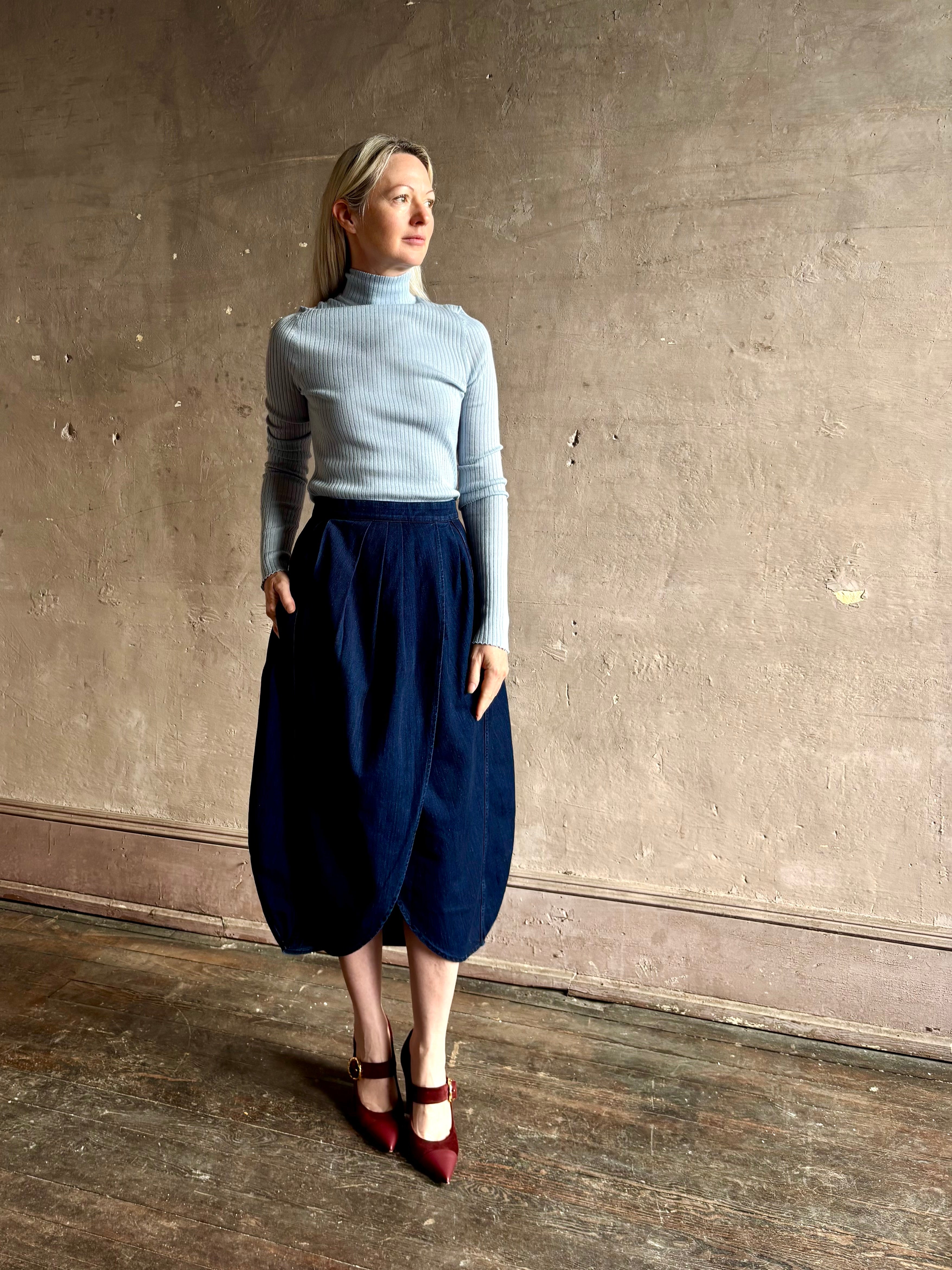 Woman wearing Rachel Comey dark wash denim midi Sobre skirt wrap-style front slit tulip design and side pockets
