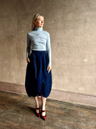 Woman wearing Rachel Comey dark wash denim midi Sobre skirt wrap-style front slit tulip design and side pockets