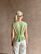 Mature woman wearing light green white horizontally striped Rachel Comey top  gathered twist waist detail reversable