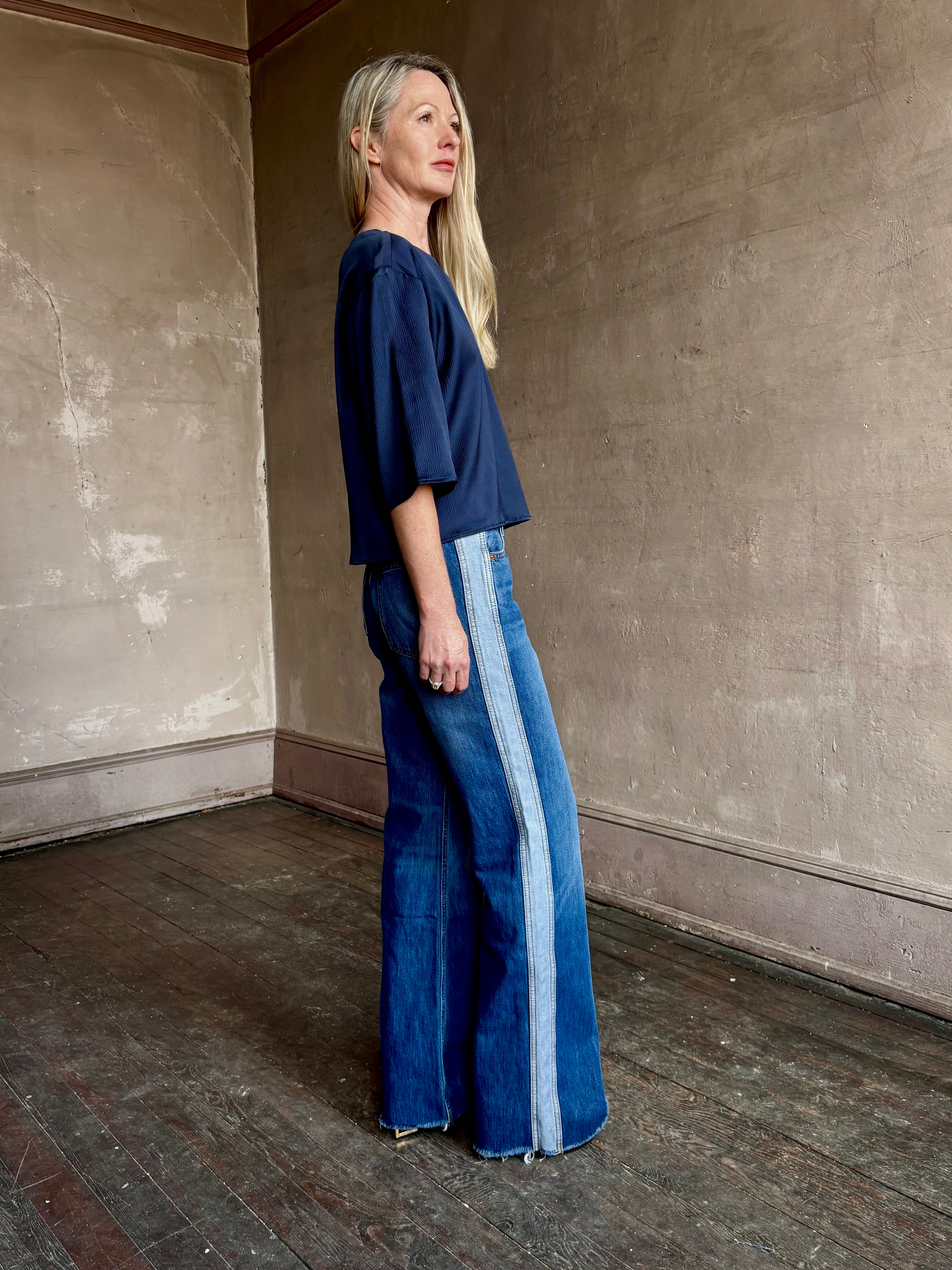 Image of mature woman wearing mid-rise jean ReDone track Californian denim with light blue stripe down side in Viper blue wash