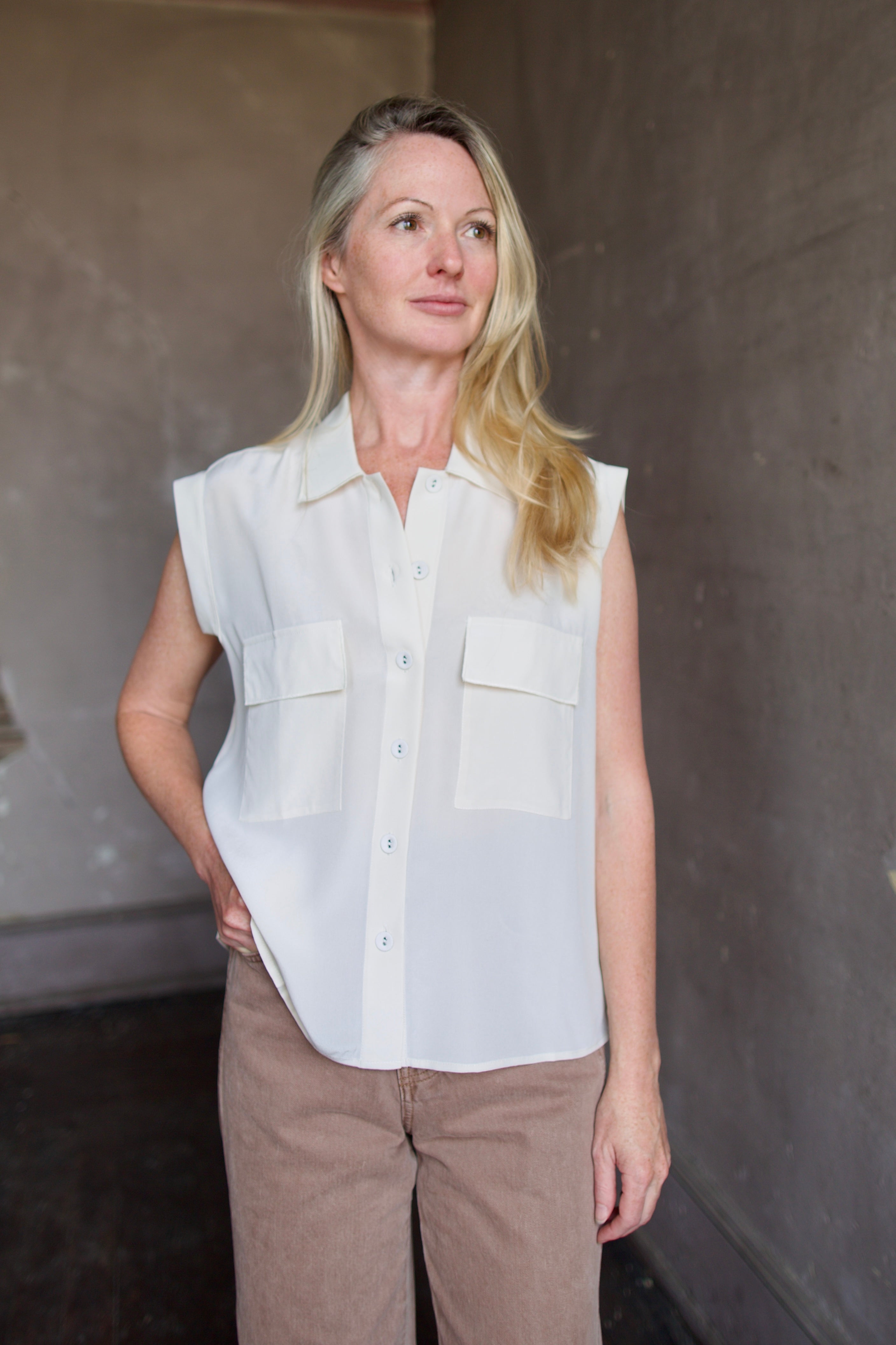 Model wearing a beige silk button down blouse by Rachel Comey in a modern silhouette
