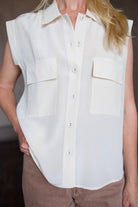 Model wearing a beige silk button down blouse by Rachel Comey in a modern silhouette