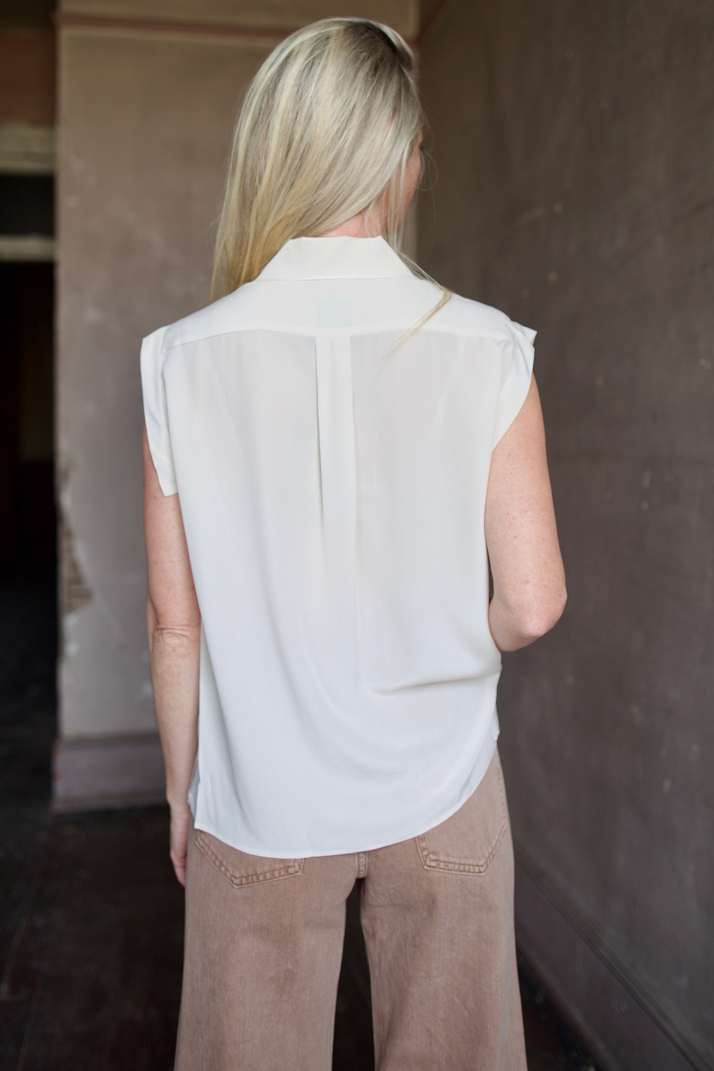 Model wearing a beige silk button down blouse by Rachel Comey in a modern silhouette