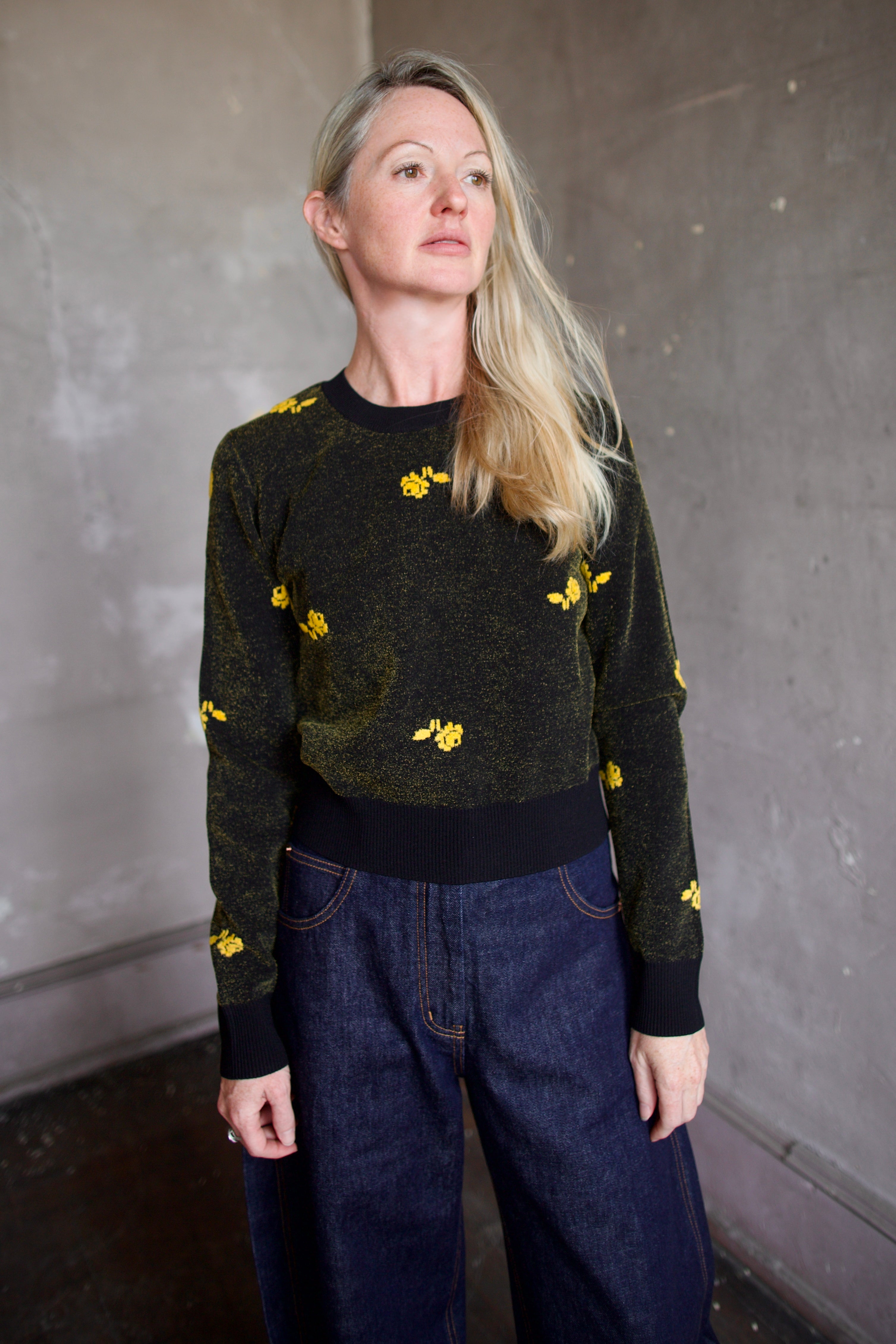 Model wearing a black Rachel Comey sweater with yellow floral patterns 