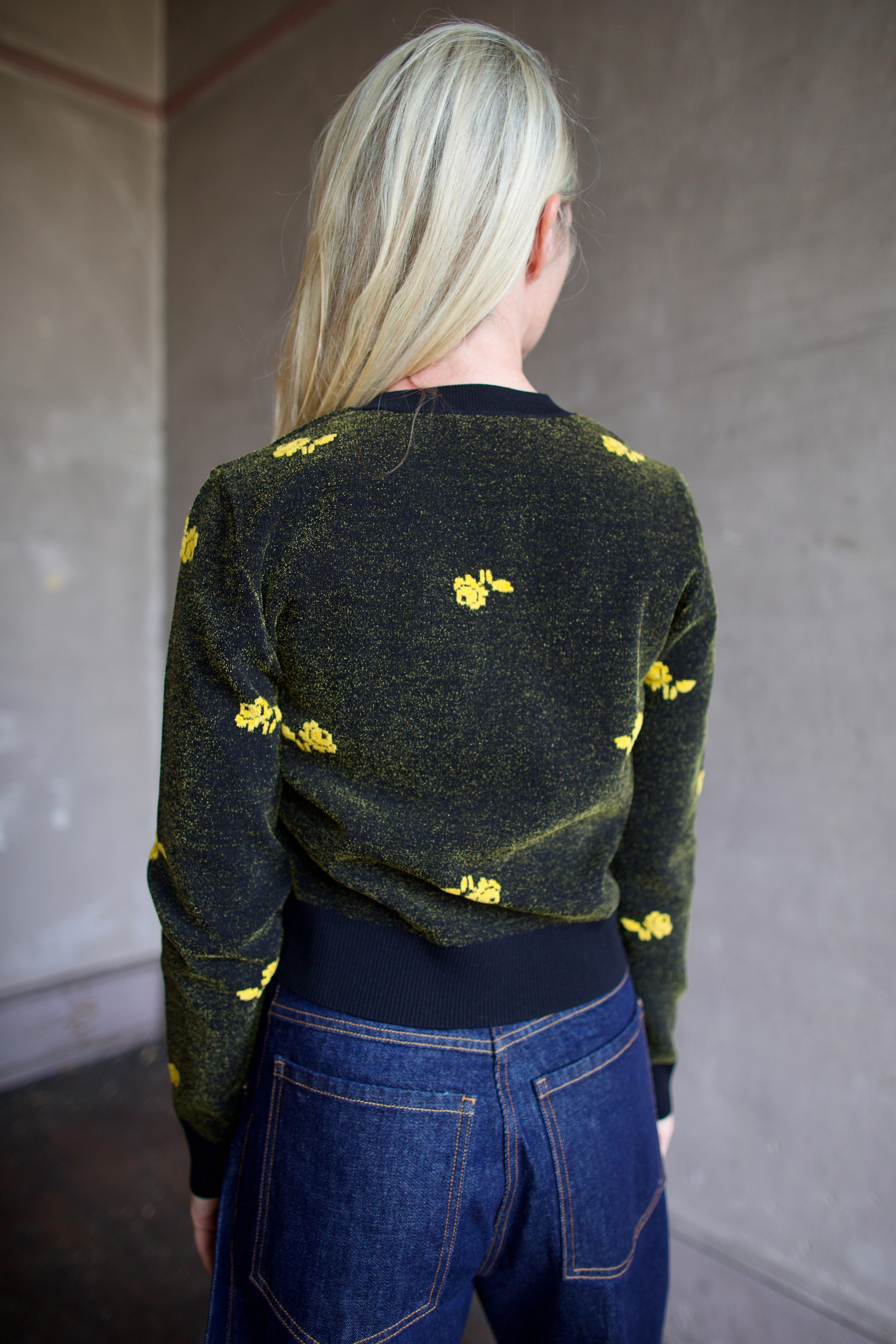 Model wearing a black Rachel Comey sweater with yellow floral patterns 