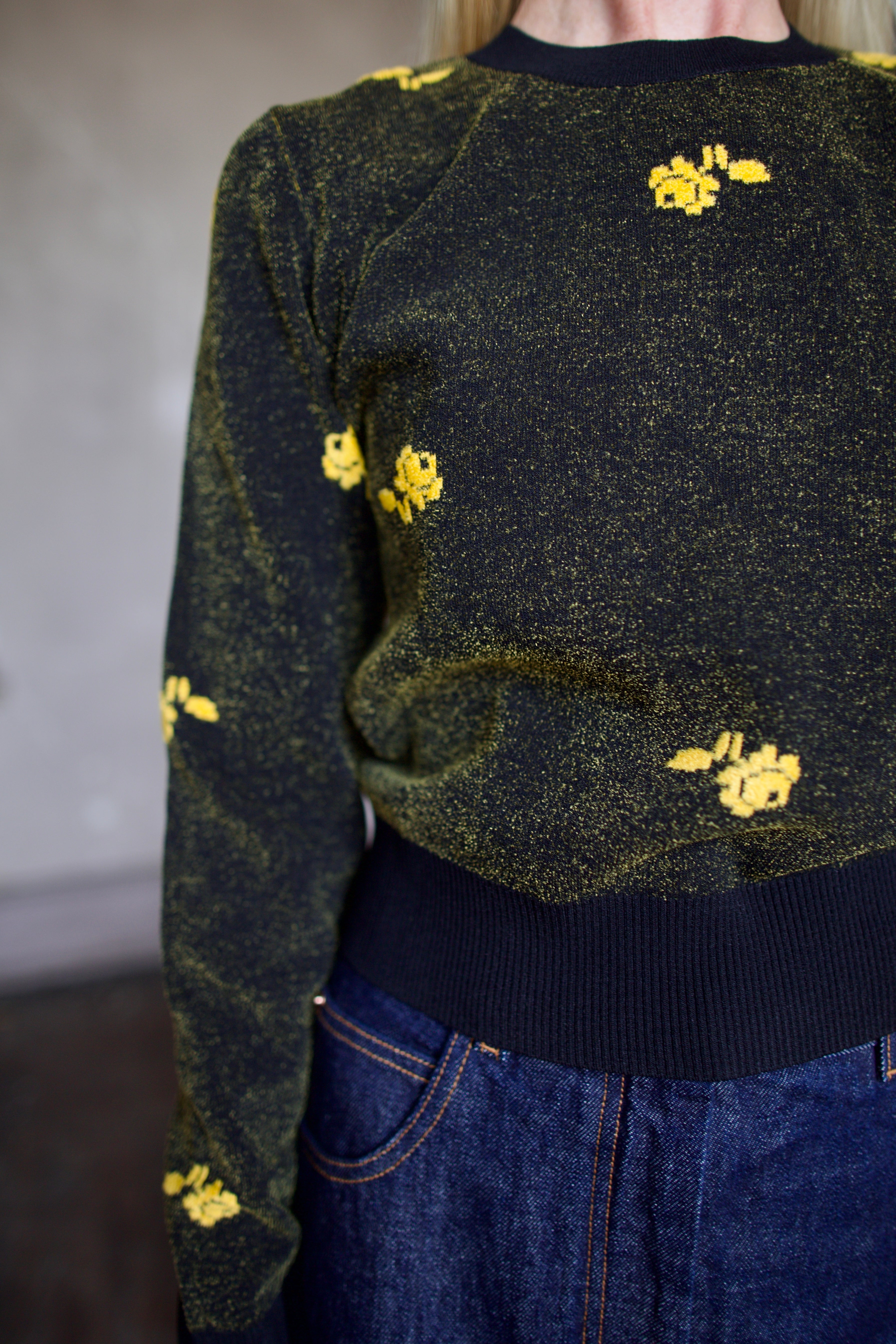 Model wearing a black Rachel Comey sweater with yellow floral patterns 
