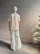 Mature woman wearing a beige retro inspired blouse with scalloped red trim by New York based Women's clothing designer Rachel Comey in raimey