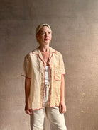 Mature woman wearing a beige retro inspired blouse with scalloped red trim by New York based Women's clothing designer Rachel Comey in raimey