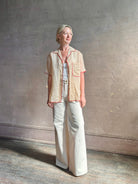 Mature woman wearing a beige retro inspired blouse with scalloped red trim by New York based Women's clothing designer Rachel Comey in raimey