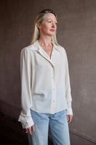 Model wearing a beige silk button down timeless blouse by Rachel Comey
