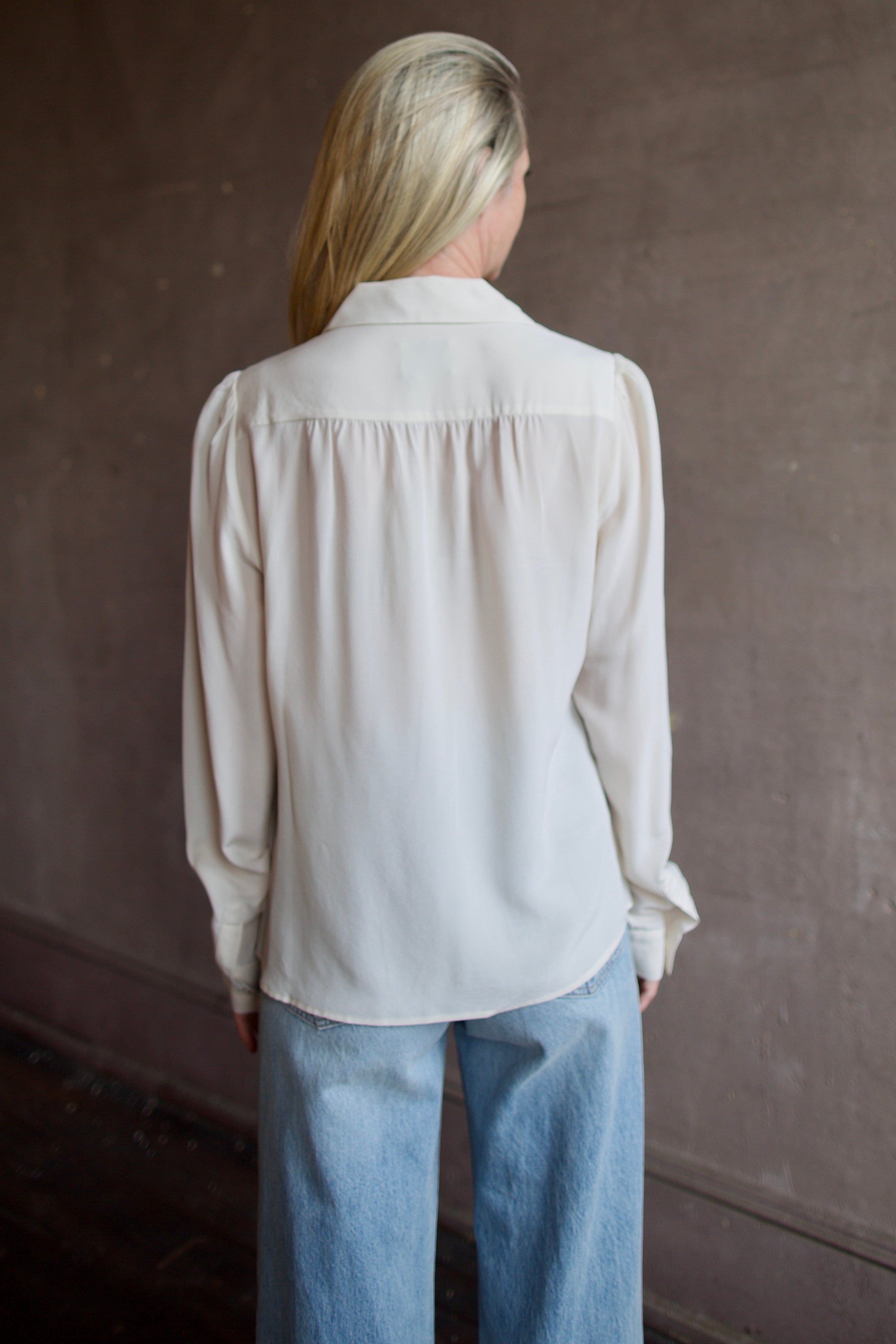 Model wearing a beige silk button down timeless blouse by Rachel Comey