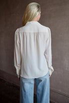 Model wearing a beige silk button down timeless blouse by Rachel Comey