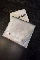 Photo of a silver metallic Rachel Comey leather wallet with two snap buttons closure