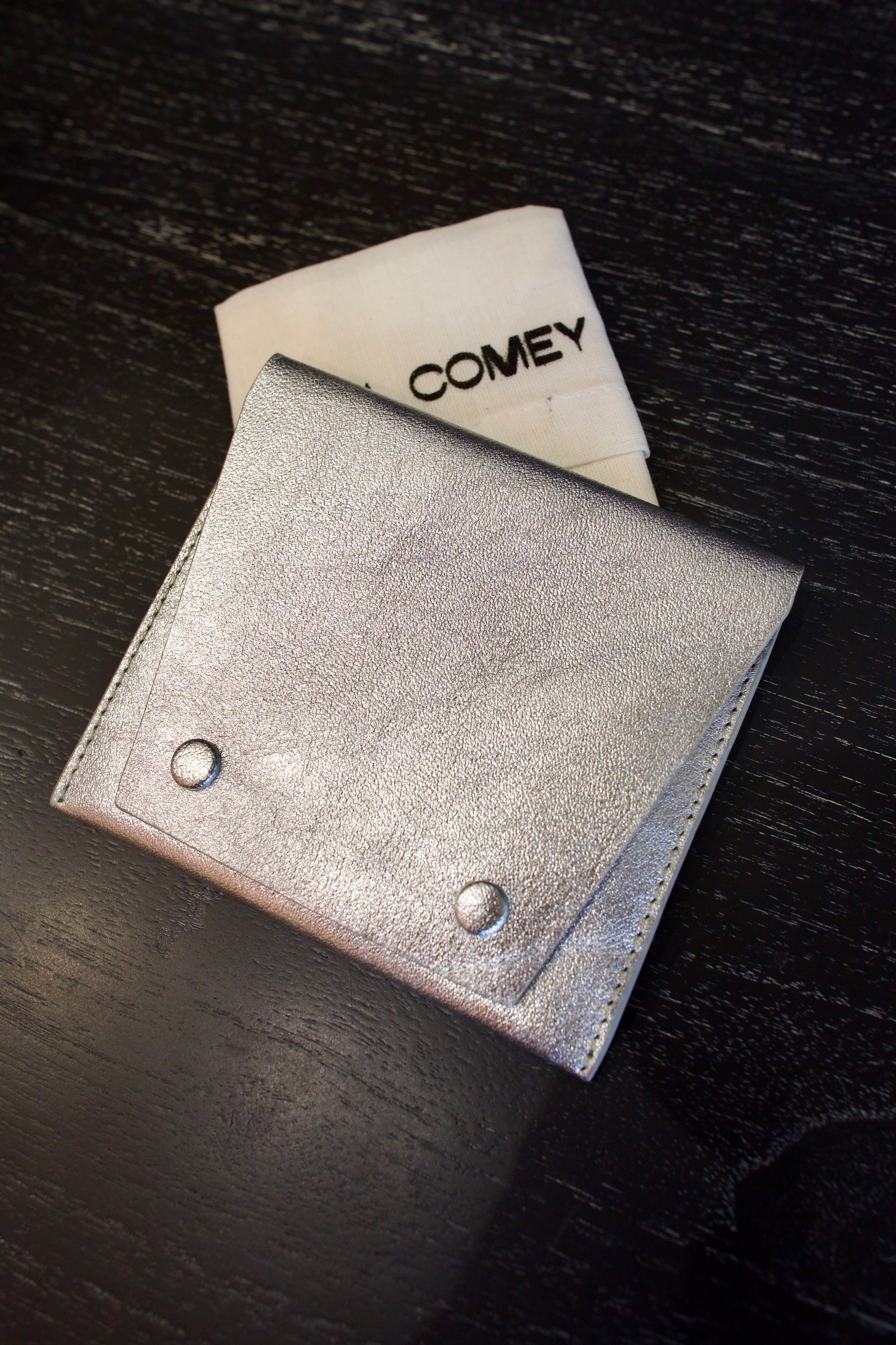 Photo of a silver metallic Rachel Comey leather wallet with two snap buttons closure