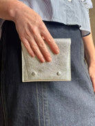 Photo of a silver metallic Rachel Comey leather wallet with two snap buttons closure