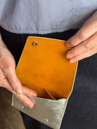 Photo of a silver metallic Rachel Comey leather wallet with two snap buttons closure