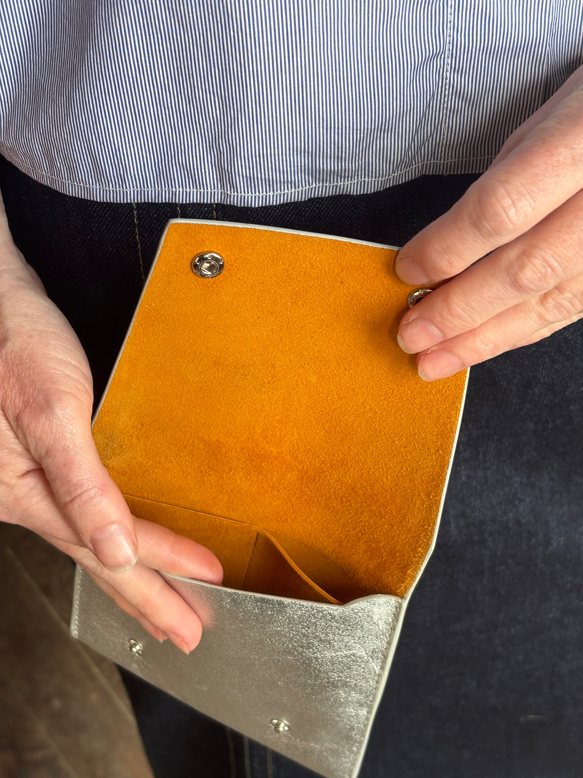 Photo of a silver metallic Rachel Comey leather wallet with two snap buttons closure