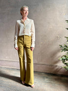Mature woman wearing Premium Baby Alpaca Mulberry Silk Calma shirt by Rachel Comey with button front, long sleeves and collar rendered in cream