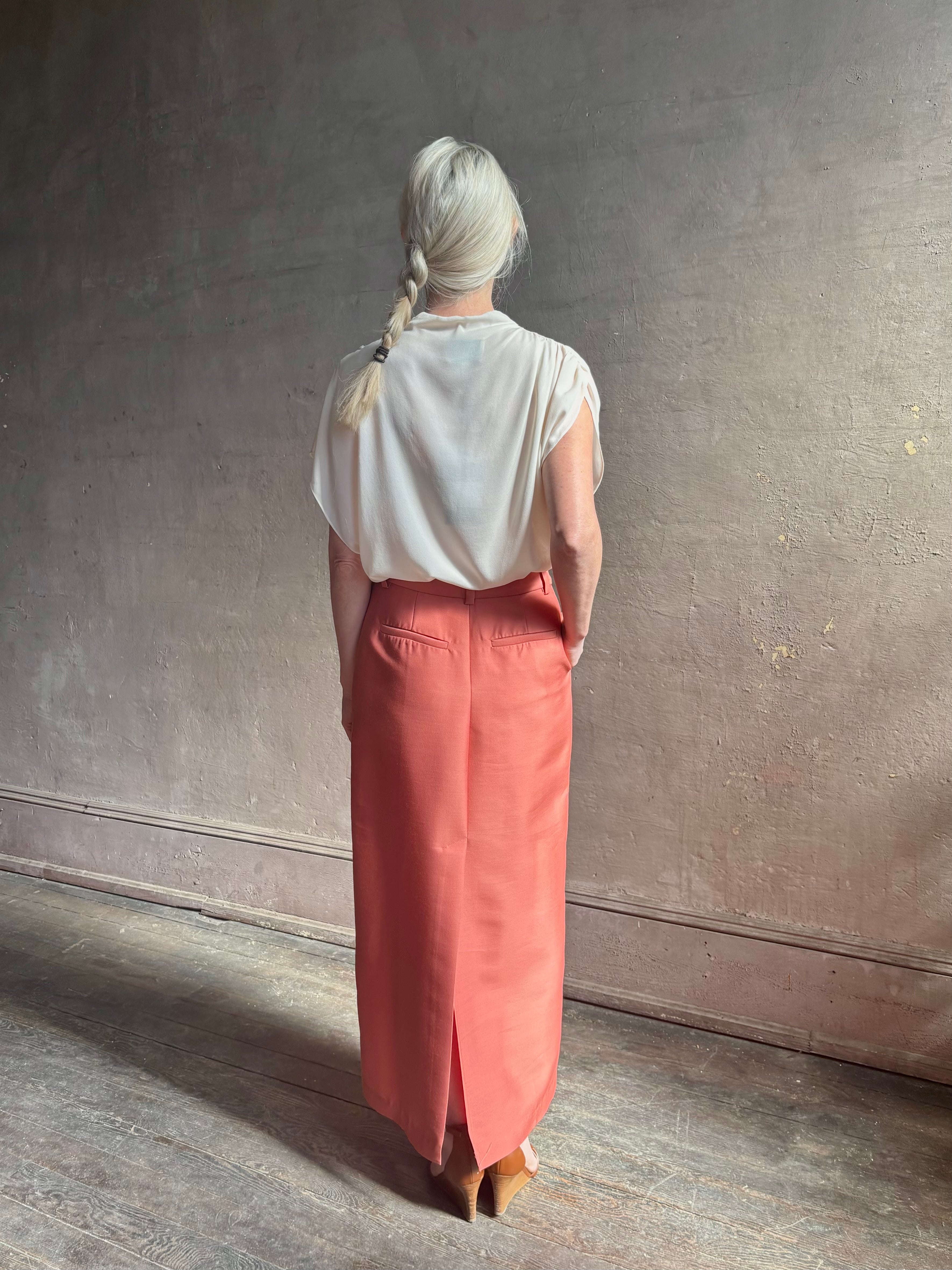 Mature woman wearing premium wool silk  women's designer Rachel Comey Cosa maxi Skirt with tailored waistband, belt loops and back vent rendered in a vibrant warm pink hue