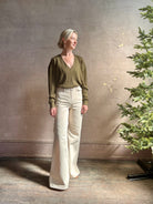 Mature woman wearing luxury Cashmere Silk Marion V-Neck designer Sweater by Rachel Comey in olive green with long sleeves and linear weave