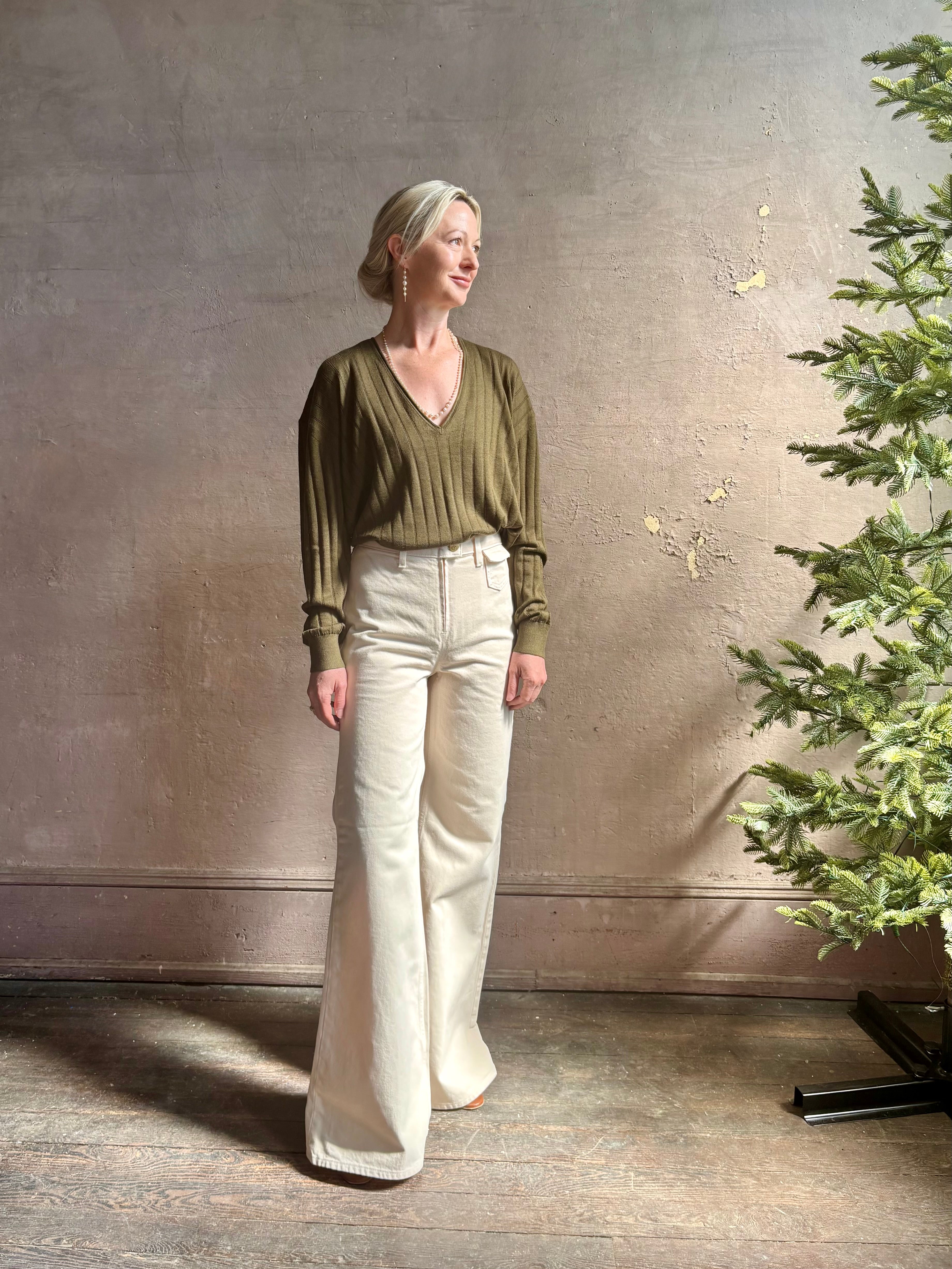 Mature woman wearing luxury Cashmere Silk Marion V-Neck designer Sweater by Rachel Comey in olive green with long sleeves and linear weave