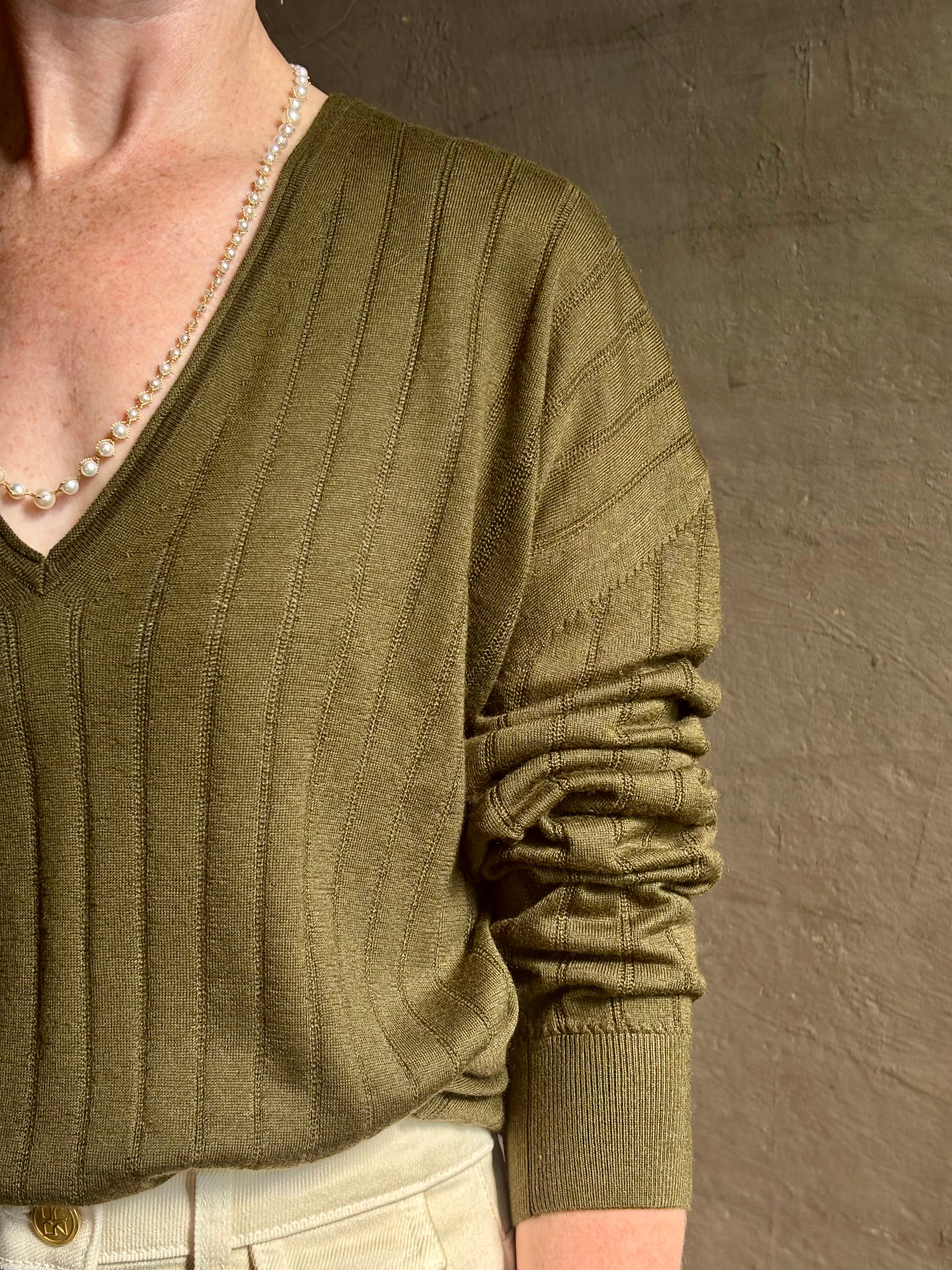 Mature woman wearing luxury Cashmere Silk Marion V-Neck designer Sweater by Rachel Comey in olive green with long sleeves and linear weave
