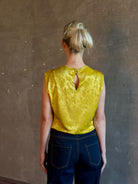 Mature woman wearing Rachel Comey Primula Pique Knit Top in Mustard yellow waterfall front tone-on-tone jacquard floral made in the USA
