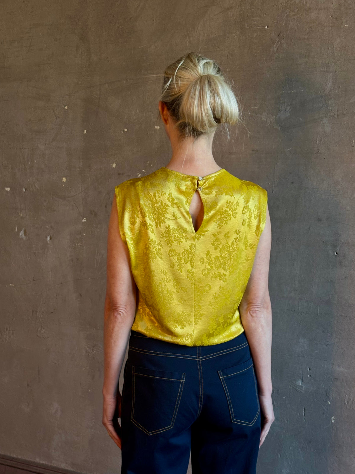 Mature woman wearing Rachel Comey Primula Pique Knit Top in Mustard yellow waterfall front tone-on-tone jacquard floral made in the USA