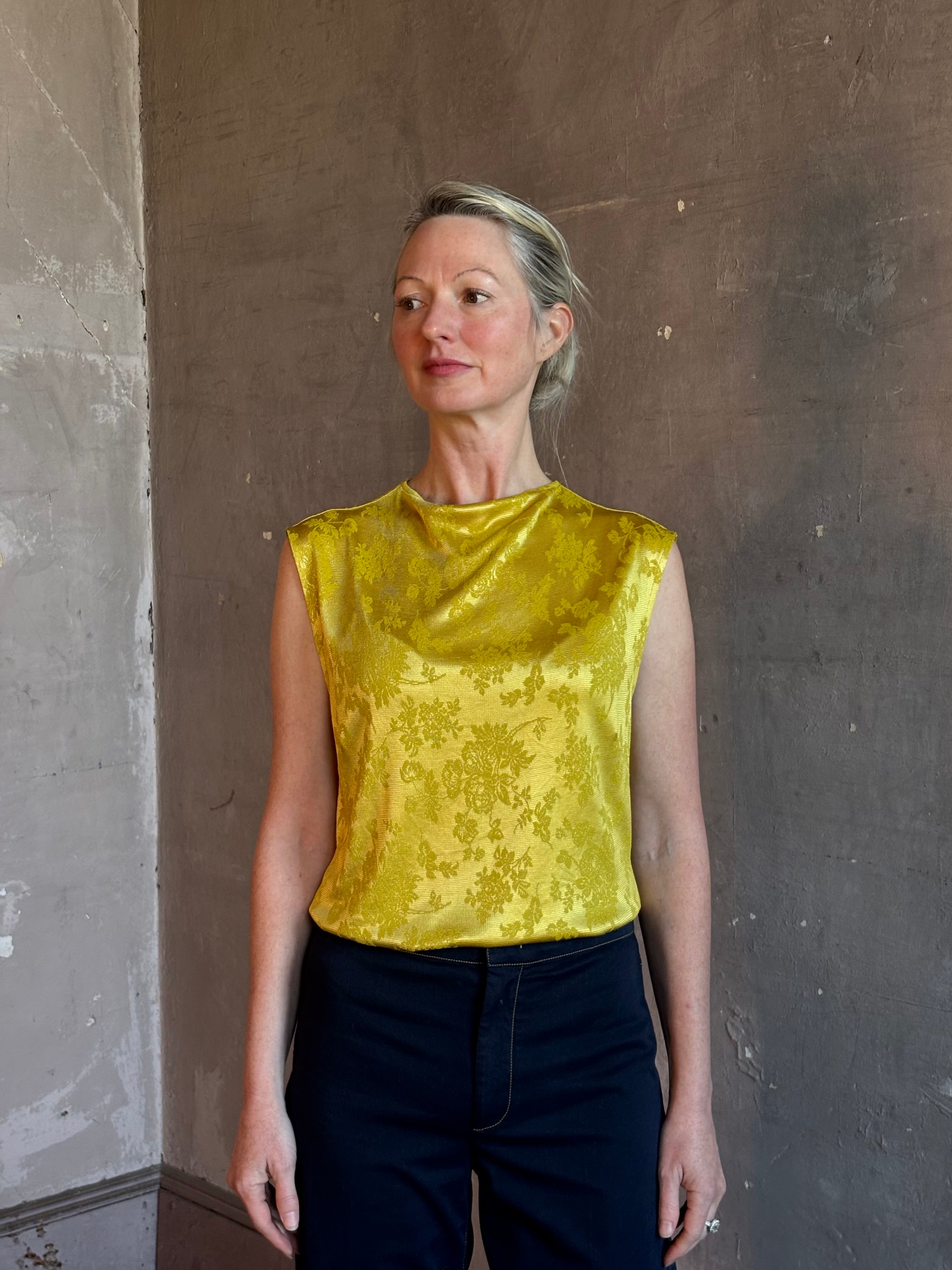 Mature woman wearing Rachel Comey Primula Pique Knit Top in Mustard yellow waterfall front tone-on-tone jacquard floral made in the USA