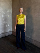 Mature woman wearing Rachel Comey Primula Pique Knit Top in Mustard yellow waterfall front tone-on-tone jacquard floral made in the USA