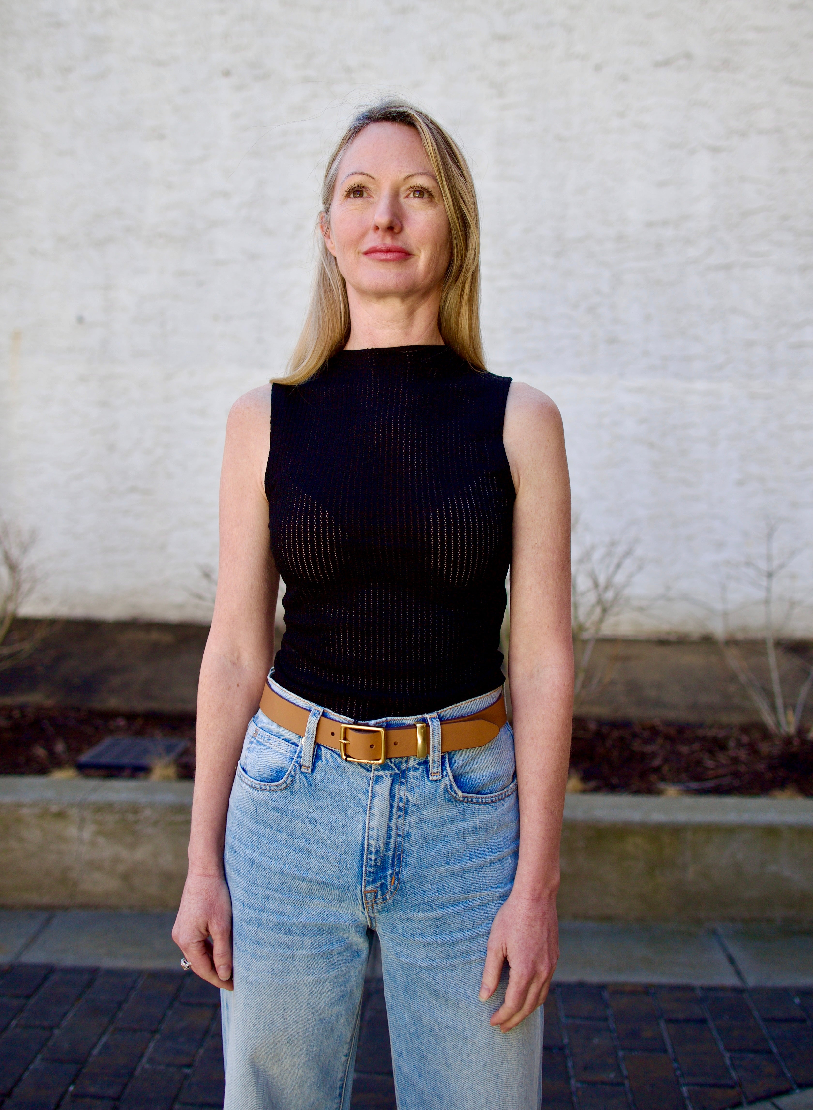 Woman wearing the Rag and Bone Molly Mock Neck black Top in semi-sheer knit construction and expertly designed minimalist silhouette