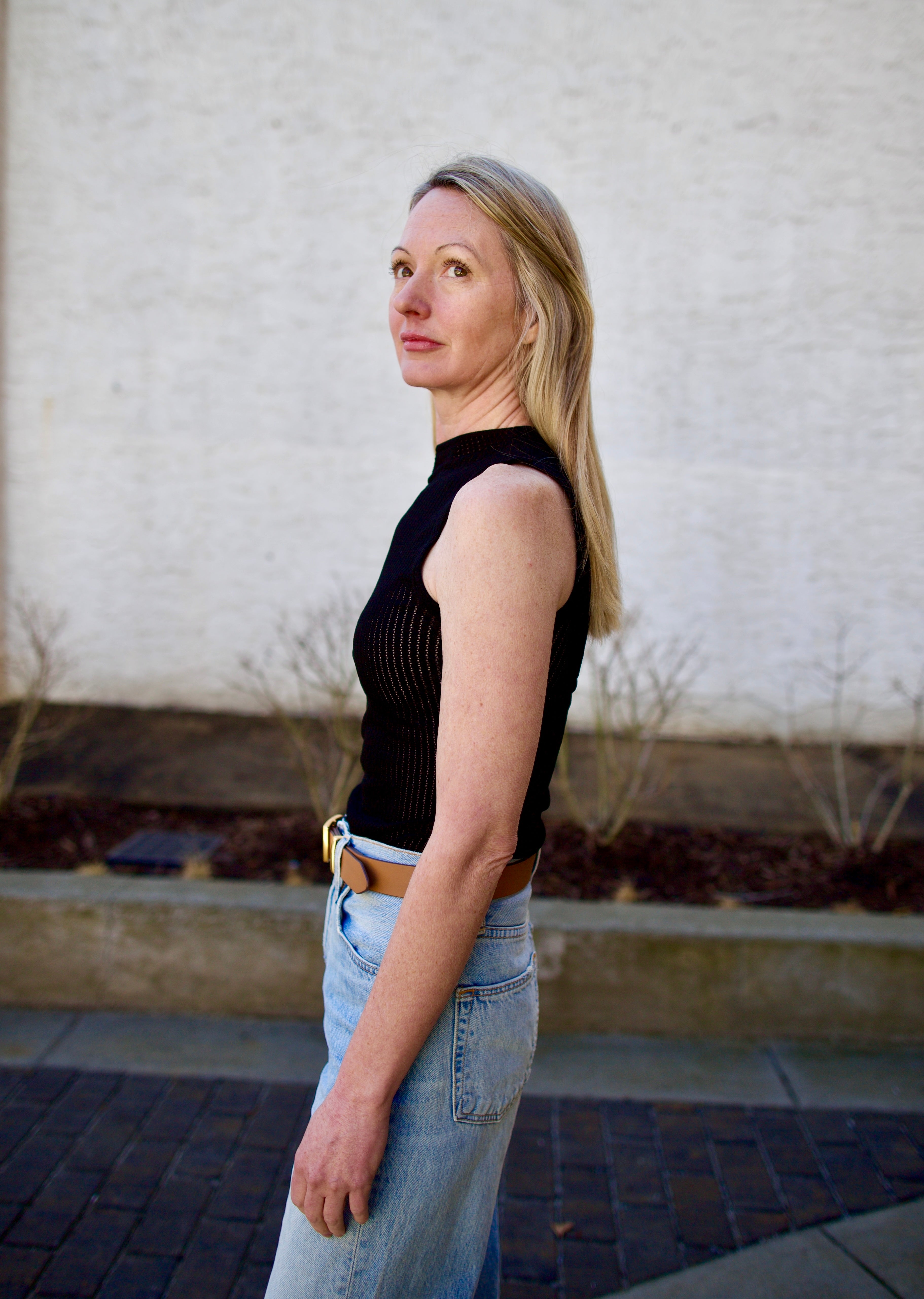 Woman wearing the Rag and Bone Molly Mock Neck black Top in semi-sheer knit construction and expertly designed minimalist silhouette