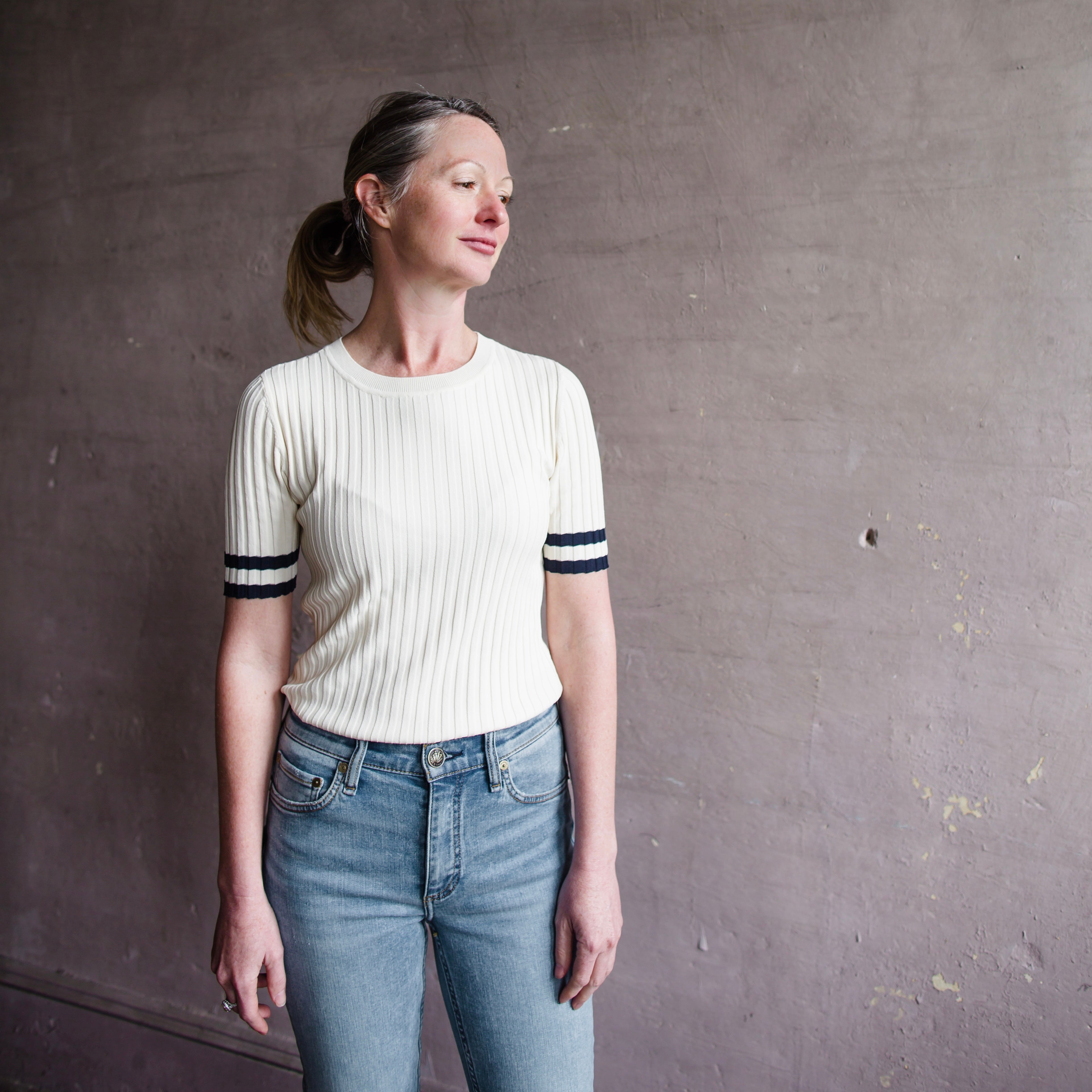 Image featuring a woman wearing the rag and bone Madison top showcases a striped trim at the cuffs and hem ribbed crewneck with short sleeves, in an easy pull over.