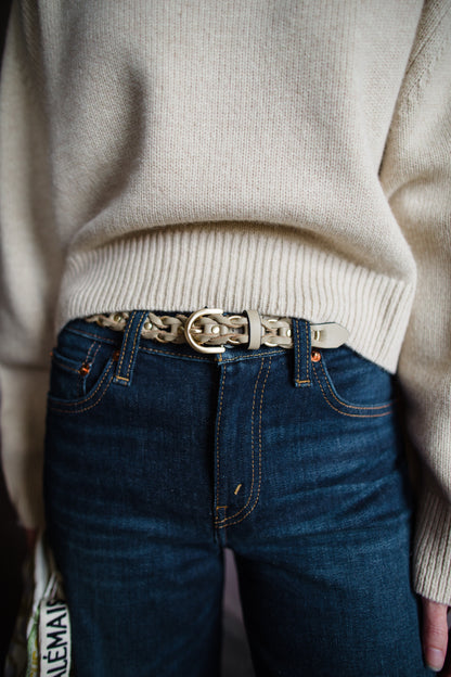 Image of a woman wearing the Rag & Bone Aria taupe leather-wrapped gold metal belt gives dimension to this belt, featuring a rounded pin buckle closure.