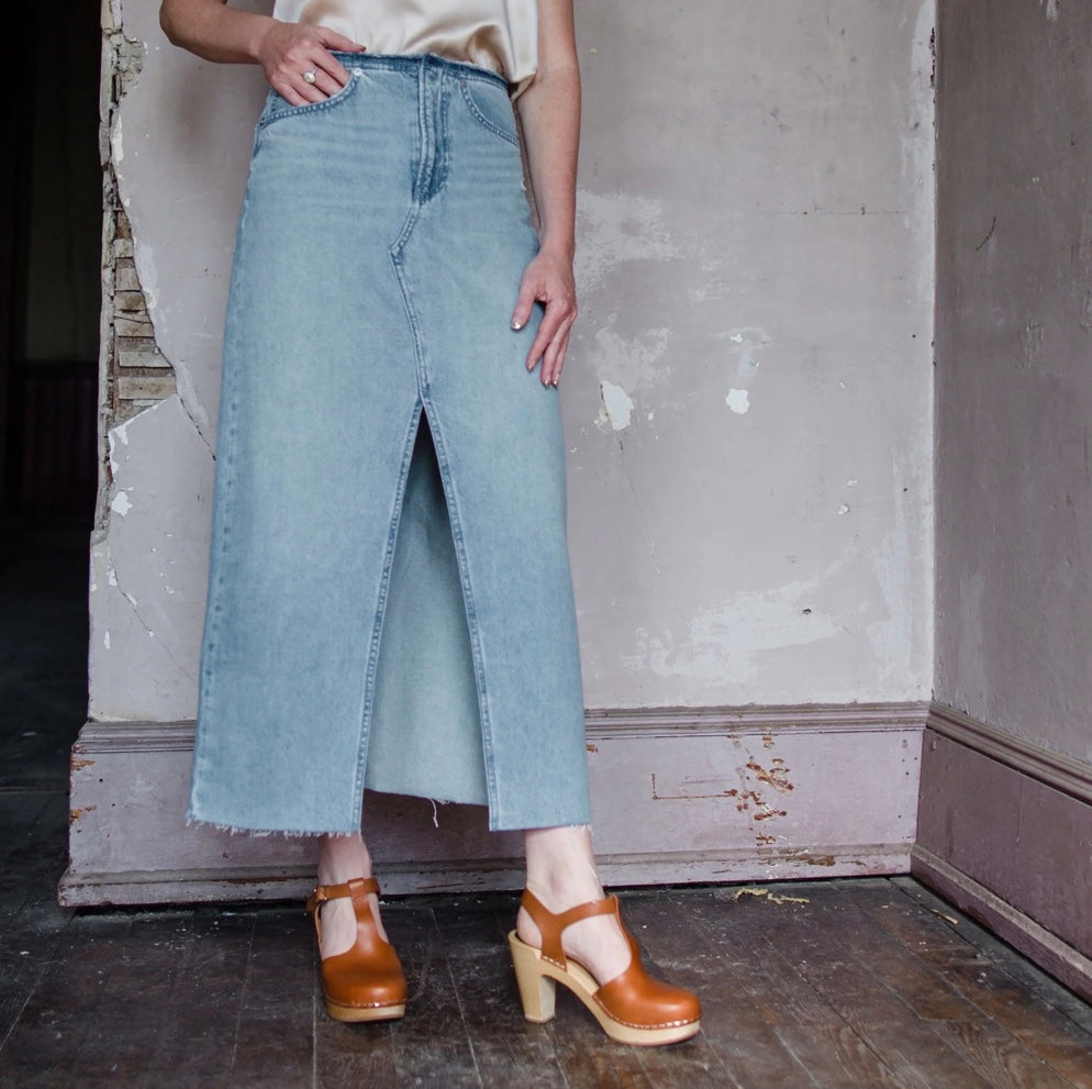 Image featuring a woman wearing a Rag & Bone Clara denim midi skirt features a raw hem, cut-off waistband and high slit.